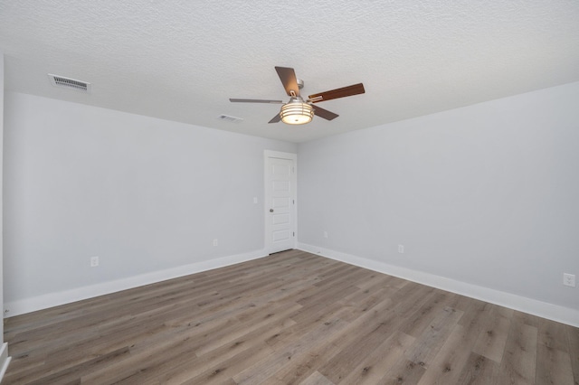 spare room with visible vents, ceiling fan, baseboards, and wood finished floors