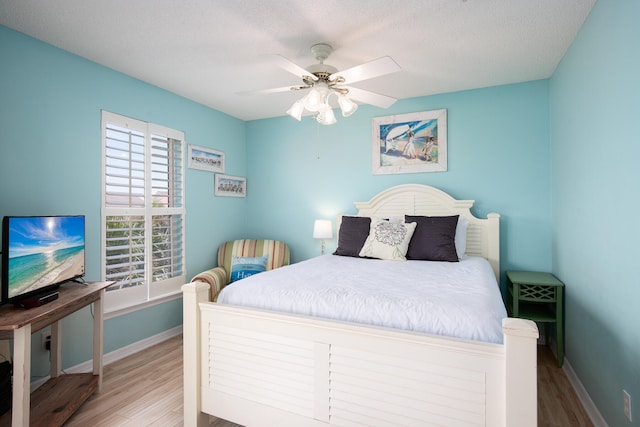 bedroom with ceiling fan, light wood-type flooring, and a textured ceiling