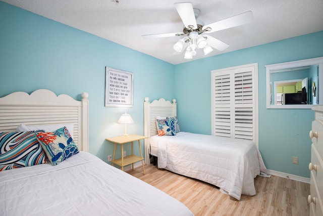 bedroom featuring ceiling fan, light wood-type flooring, and a textured ceiling