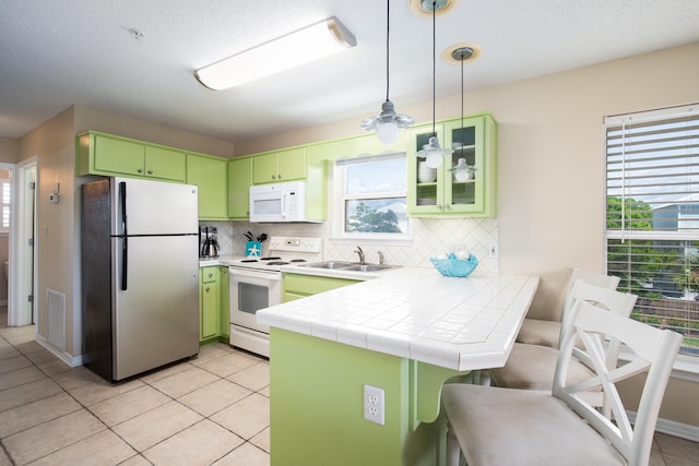 kitchen with white appliances, tile countertops, light tile patterned floors, decorative backsplash, and kitchen peninsula