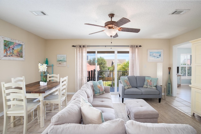 living room with ceiling fan, a wealth of natural light, light tile patterned flooring, and a textured ceiling