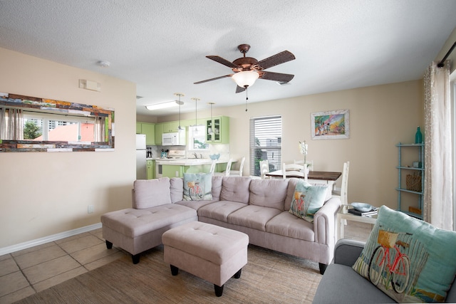 living room with ceiling fan, light tile patterned flooring, sink, and a textured ceiling