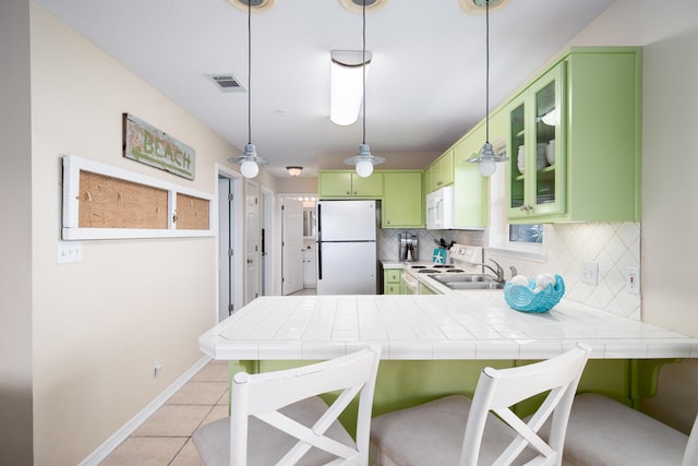 kitchen with kitchen peninsula, backsplash, green cabinets, and white appliances