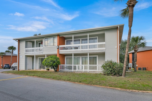 view of front of house featuring a balcony and a front lawn