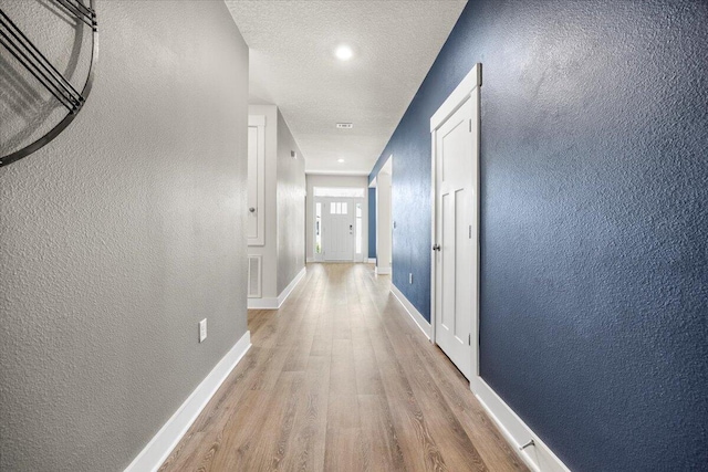 corridor featuring a textured ceiling and light hardwood / wood-style flooring