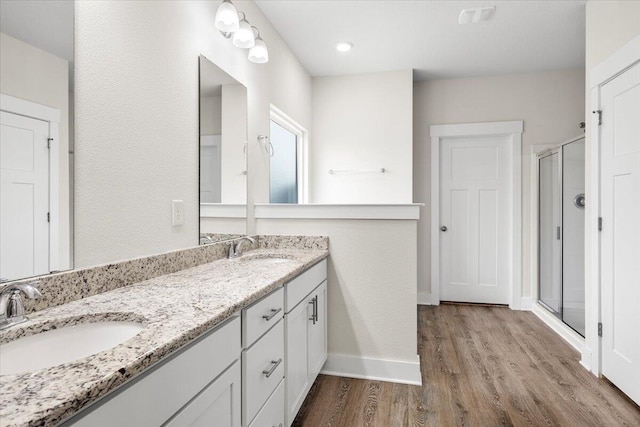 bathroom featuring double vanity, a shower with shower door, and hardwood / wood-style floors