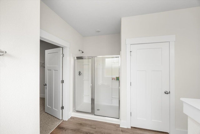 bathroom featuring a shower with shower door and wood-type flooring