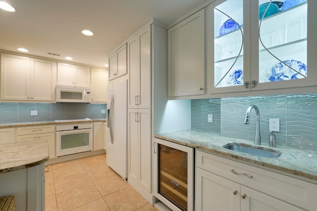 kitchen with tasteful backsplash, white appliances, light tile patterned floors, white cabinetry, and wine cooler