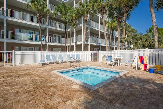 view of swimming pool with a patio area, fence, and a hot tub