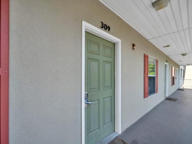 entrance to property with covered porch and stucco siding