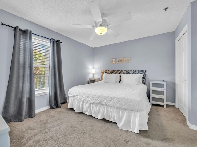 carpeted bedroom with ceiling fan, baseboards, and a textured ceiling