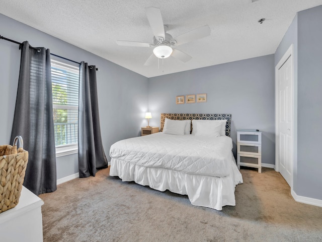 carpeted bedroom with a ceiling fan, a textured ceiling, and baseboards