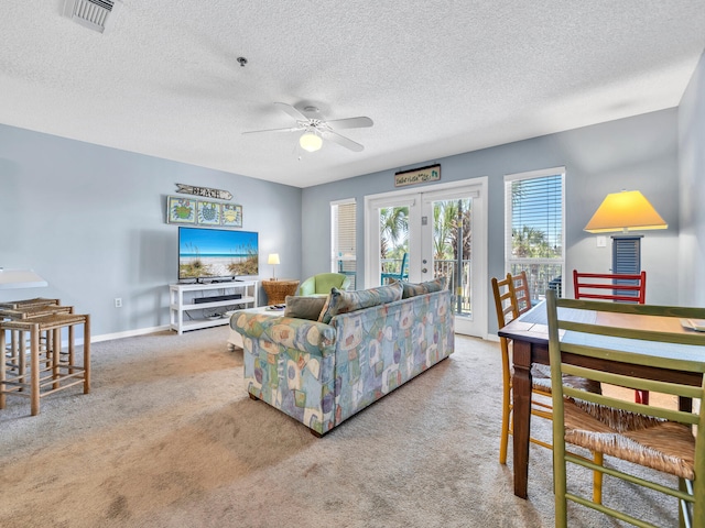 living area with light carpet, a ceiling fan, visible vents, baseboards, and french doors