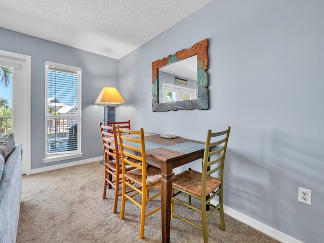 dining space with a textured ceiling, carpet flooring, and baseboards