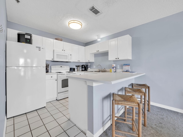 kitchen featuring white appliances, light countertops, a peninsula, and white cabinetry