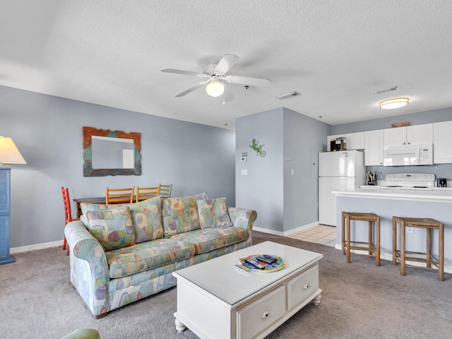 living area featuring light colored carpet, visible vents, ceiling fan, and a textured ceiling