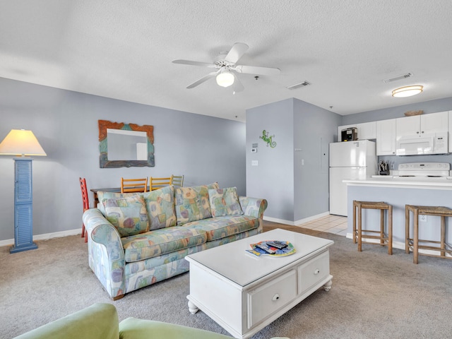 living room with light carpet, ceiling fan, visible vents, and a textured ceiling