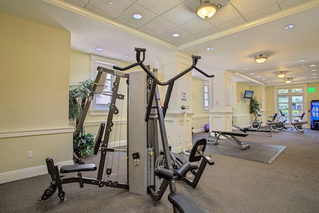 exercise room with crown molding, a paneled ceiling, and ornate columns