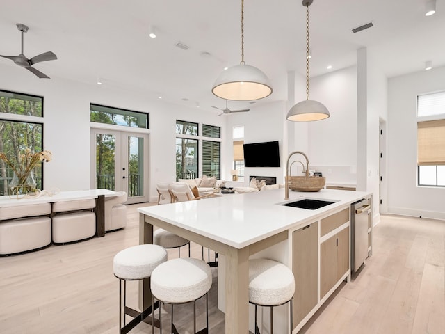 kitchen featuring pendant lighting, light wood-type flooring, plenty of natural light, and sink