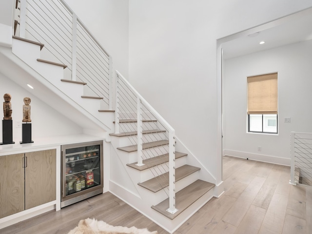 stairway featuring wood-type flooring, wine cooler, and bar area