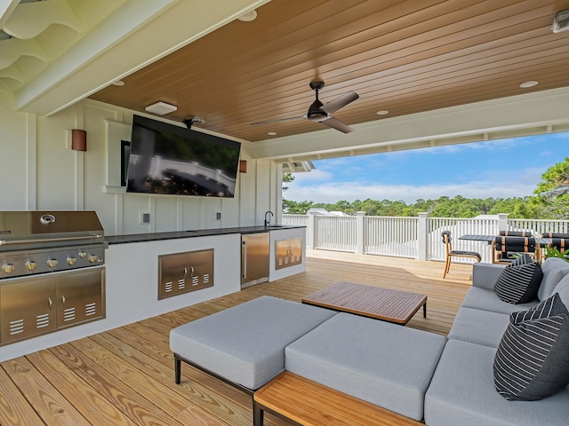 view of patio / terrace featuring ceiling fan, sink, grilling area, a wooden deck, and an outdoor kitchen