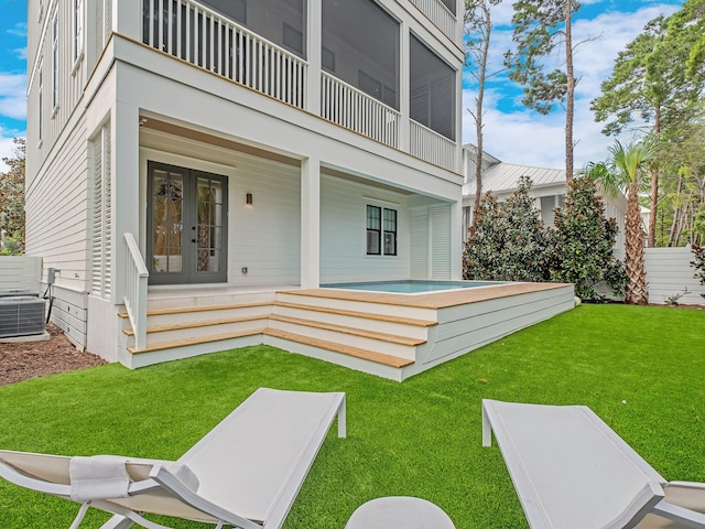 rear view of house featuring a yard, a balcony, french doors, and central AC unit