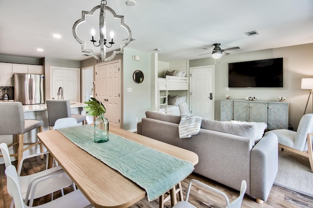 dining area with ceiling fan with notable chandelier and light wood-type flooring