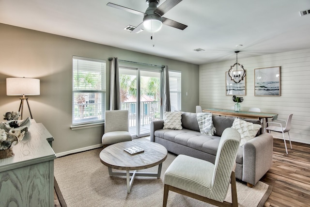 living room with wood-type flooring and ceiling fan with notable chandelier