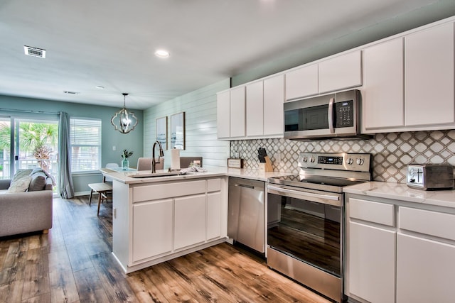 kitchen with sink, appliances with stainless steel finishes, light hardwood / wood-style flooring, and white cabinetry