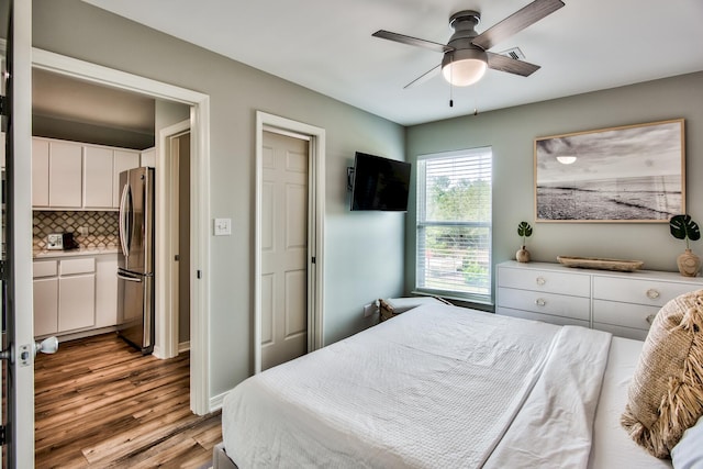 bedroom featuring ceiling fan, light hardwood / wood-style flooring, and stainless steel fridge