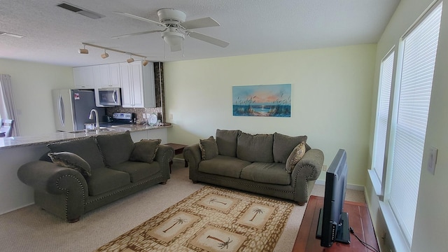 living area featuring ceiling fan, a textured ceiling, and visible vents