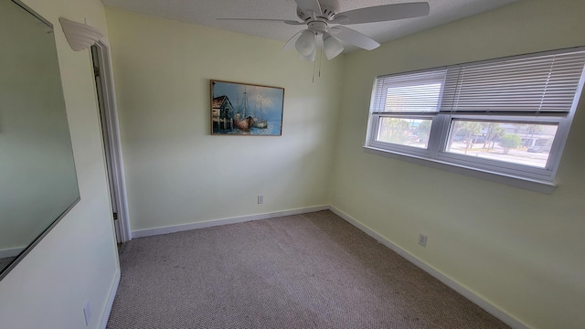 unfurnished room featuring a ceiling fan, baseboards, and carpet