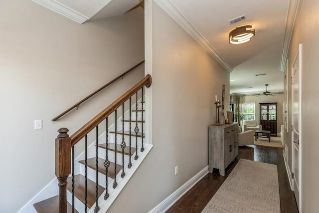 stairs with ceiling fan, crown molding, and dark wood-type flooring