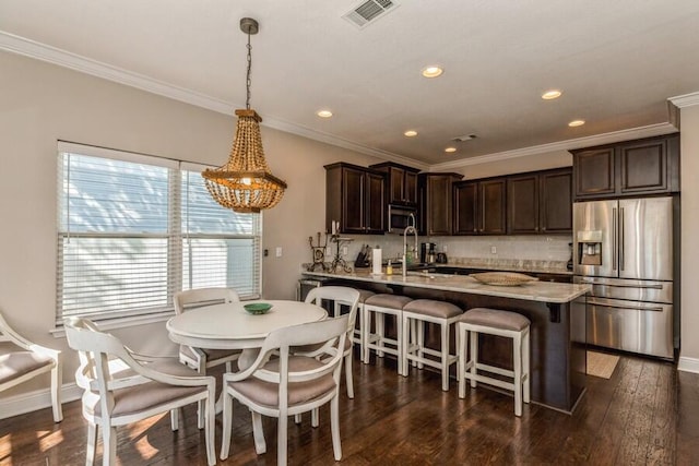 kitchen featuring hanging light fixtures, dark wood-type flooring, backsplash, and stainless steel appliances