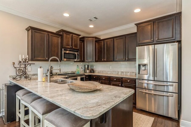 kitchen featuring stainless steel appliances, light stone counters, dark brown cabinets, decorative backsplash, and dark wood-type flooring