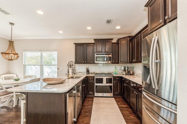 kitchen with dark wood-type flooring, light stone counters, stainless steel appliances, pendant lighting, and dark brown cabinetry