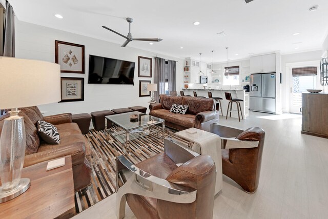 living room featuring ornamental molding, a healthy amount of sunlight, and light wood-type flooring