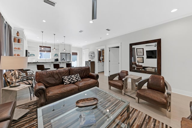 living room with sink, ornamental molding, and light hardwood / wood-style floors