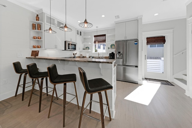 kitchen with a breakfast bar, white cabinetry, appliances with stainless steel finishes, kitchen peninsula, and pendant lighting