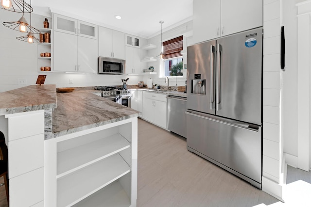 kitchen with sink, white cabinetry, premium appliances, decorative light fixtures, and kitchen peninsula