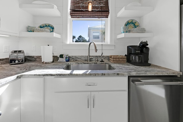 kitchen featuring light stone countertops, sink, stainless steel dishwasher, and white cabinets