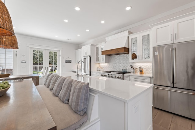 kitchen with white cabinetry, range, high end refrigerator, and premium range hood