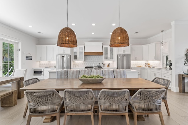 dining space featuring ornamental molding, light hardwood / wood-style floors, and sink