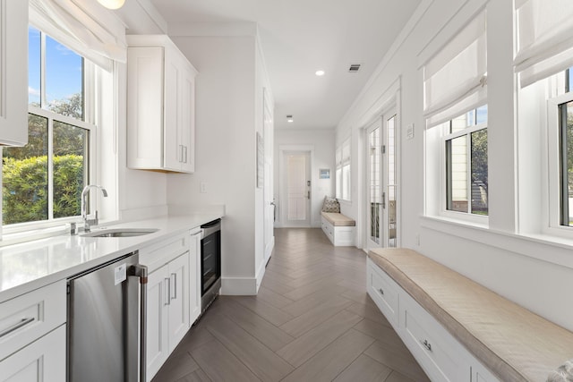 kitchen featuring sink, white cabinetry, dark parquet flooring, stainless steel dishwasher, and beverage cooler