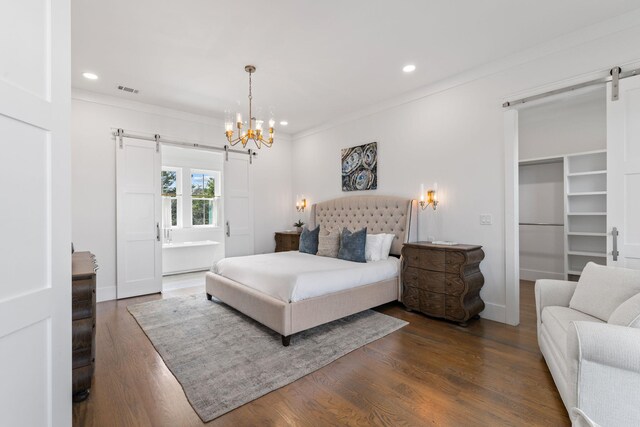 bedroom with ornamental molding, dark hardwood / wood-style flooring, a barn door, and connected bathroom