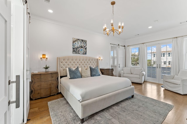 bedroom with hardwood / wood-style flooring, access to outside, crown molding, and a barn door