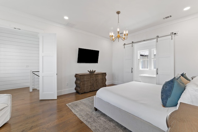 bedroom featuring ensuite bathroom, a barn door, a notable chandelier, and hardwood / wood-style floors