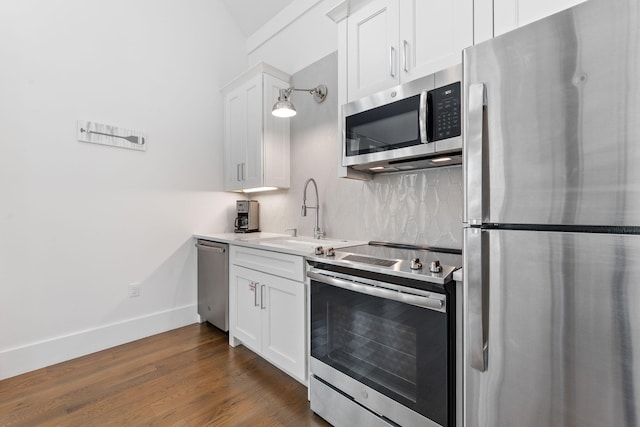 kitchen featuring white cabinets, dark wood-type flooring, hanging light fixtures, appliances with stainless steel finishes, and sink