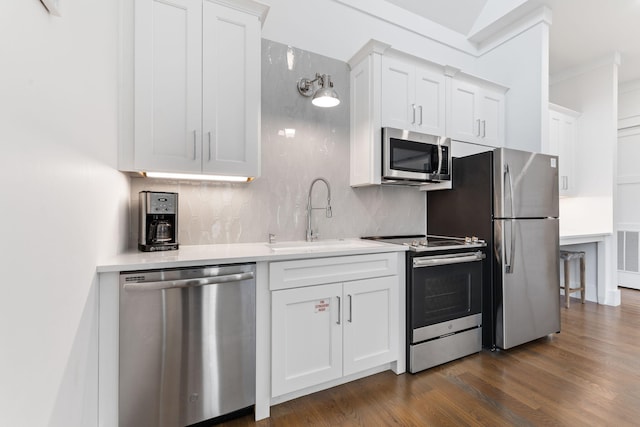 kitchen with dark wood-type flooring, sink, white cabinetry, tasteful backsplash, and appliances with stainless steel finishes