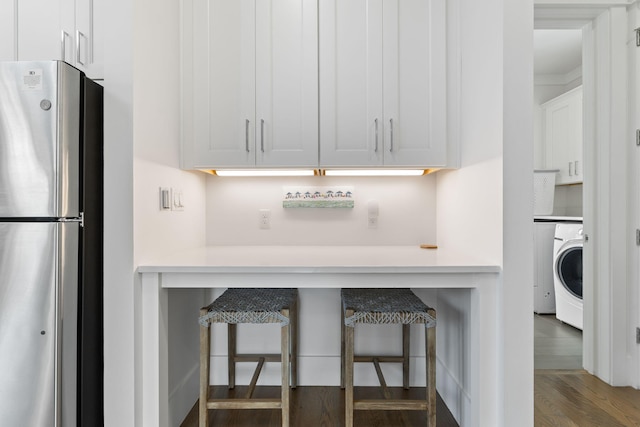 kitchen with stainless steel fridge, dark hardwood / wood-style flooring, washer / dryer, and white cabinets